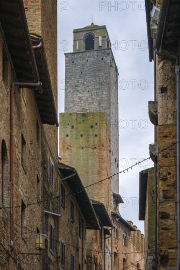 A striking view of San Gimignano's iconic medieval towers framed by narrow streets and traditional stone buildings. The rustic architecture showcases Tuscany's rich history and charm