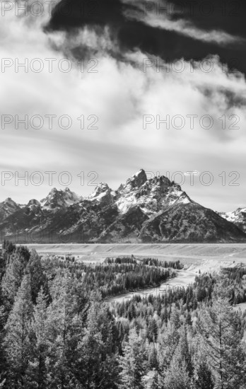 Majestic peaks of Grand Teton National Park in Wyoming captured in stunning black and white, showcasing towering mountains, lush forests, and dynamic clouds
