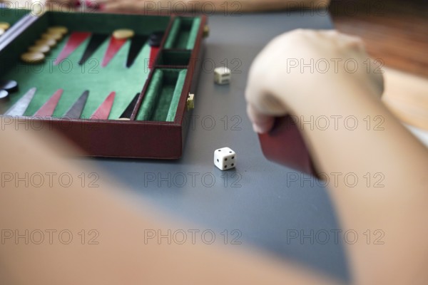 A hand throws dice beside a backgammon board, highlighting the strategic elements and excitement of the game The colorful board and dice create a vibrant atmosphere