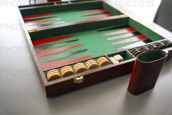 A detailed shot of a backgammon board, highlighting the checker pieces and dice inside a classic case The rich green and red colors evoke a sense of strategy and tradition