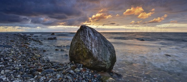 Rocky beach with boulders on the Baltic Sea at sunrise under dark skies with dramatic clouds, Jasmund National Park, Rügen Island, Mecklenburg-Western Pomerania, Germany