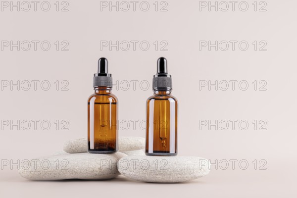 Two amber glass dropper bottles on minimalist stones, set against a neutral background Ideal for essential oils, serums, or cosmetics packaging, embodying simplicity and elegance