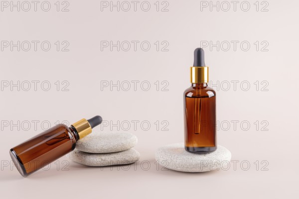 Two amber glass dropper bottles on smooth stones, featuring a minimalist aesthetic Ideal for showcasing oils or skincare products on a neutral background