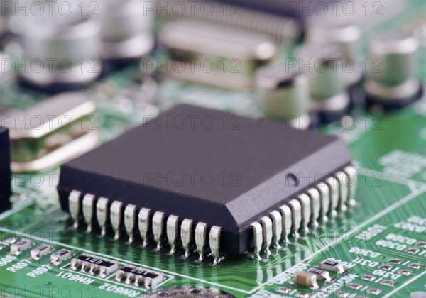 A detailed macro shot of a microchip securely mounted on a green printed circuit board, demonstrating intricate electronic design