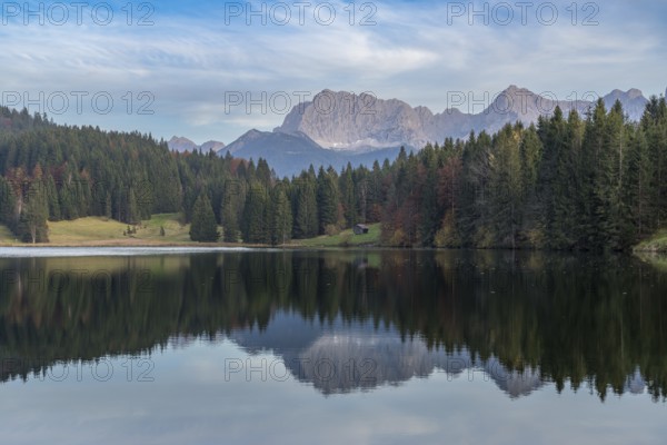 Tranquil Geroldsee with the stunning Bavarian Alps in the background Tall evergreens and rocky peaks reflect in the calm lake waters, creating a picturesque scene