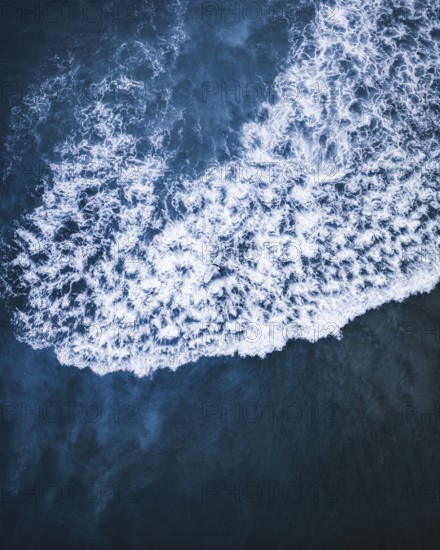 A breathtaking aerial shot of white ocean waves crashing against deep blue waters on the coast of Portugal. Perfect for themes of nature, energy, and coastal beauty