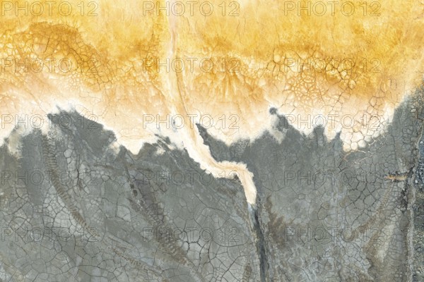 Captivating multicolored mud texture showcasing vibrant orange and gray hues The cracked surface and natural patterns create an abstract feel, inspired by Earth's organic beauty