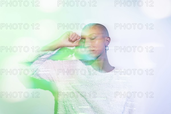 A serene image of a middle-aged woman with a shaved head, wearing a textured white top against a soft, blurred pastel background, creating a dreamy and calm atmosphere