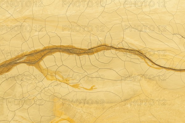 Intricate texture of golden mud with a distinct crack pattern that intertwines elegantly across the surface, ideal for abstract and nature-themed backgrounds