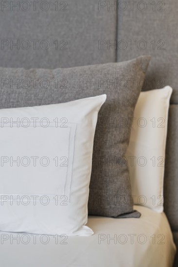 A close-up of a hotel room showcasing neatly arranged pillows on a textured headboard, highlighting soft, natural hues and inviting comfort in a modern, sophisticated setting