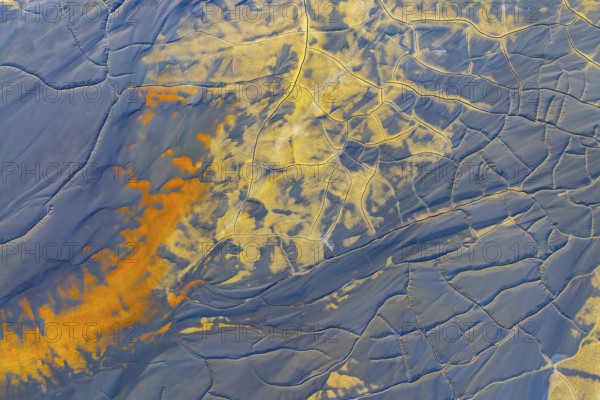 Aerial view of multicolor mud formations showcasing vibrant patterns and textures Shades of orange and blue blend artistically with intricate natural lines and shapes