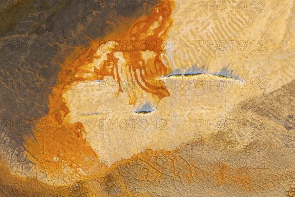 Aerial view of vibrant multicolor mud patterns showcasing orange, brown, and earthy hues The crackled textures create an abstract landscape, highlighting nature's artistry