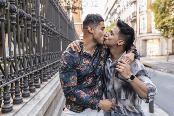 A romantic moment in Madrid as a couple shares a heartfelt kiss on a city street. Their stylish attire and the soft daylight enhance the atmosphere of love and connection