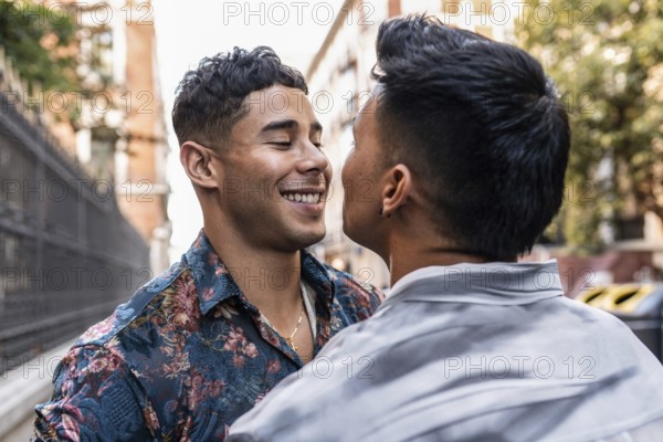 A smiling latin gay couple enjoys a romantic moment on a sunny day in Madrid. They are embracing, surrounded by urban scenery, reflecting love and happiness in the city atmosphere