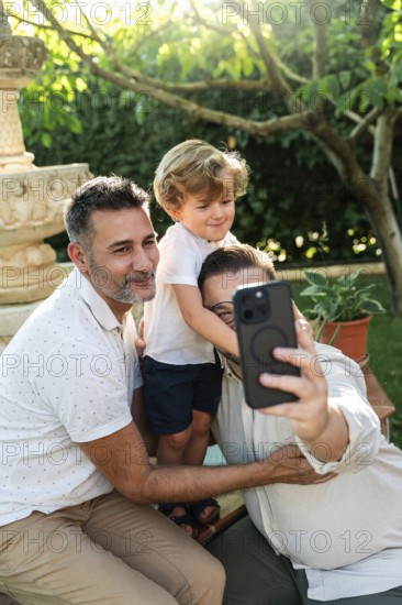 A joyful moment as a gay couple takes a selfie with their son in a sunlit garden. Embracing diversity and family love