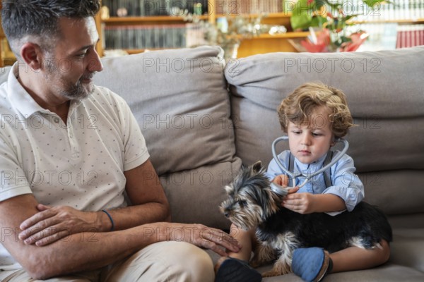 A child explores the role of a vet, using a stethoscope on a small dog, with a smiling father observing. The cozy living room setting adds warmth