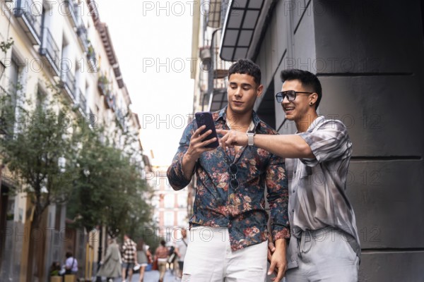 A joyful latin gay couple using a smartphone while strolling through a vibrant street in Madrid, Spain. They share a moment of connection and exploration in the bustling city