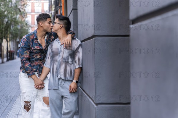 A latin gay couple shares a tender kiss while holding hands in the vibrant streets of Madrid. The urban backdrop adds a romantic and modern vibe to this intimate moment