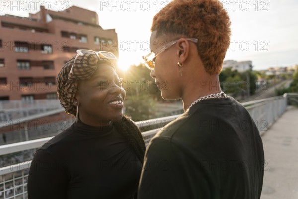 A loving LGBT multiethnic couple shares a tender moment while basking in the warm glow of the sunset at an urban park. They face one another, radiating happiness and connection