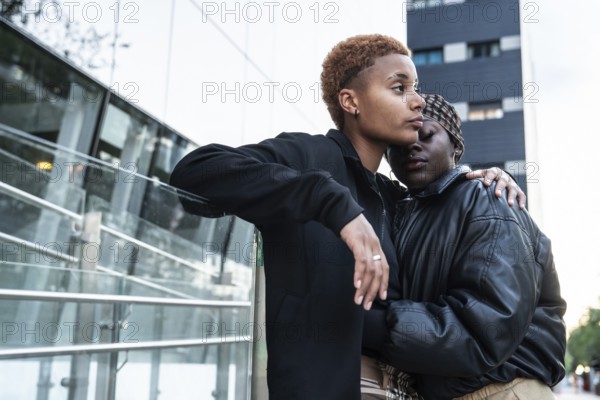 A loving LGBT multiethnic couple embraces outdoors in an urban environment. The moment captures intimacy and connection, reflecting beauty in genuine affection and love