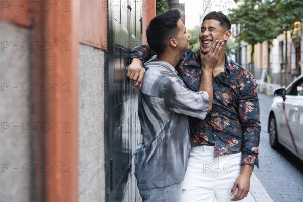 A joyful latin gay couple shares a tender moment on a vibrant street in Madrid. Their happiness and connection are beautifully captured in this urban setting