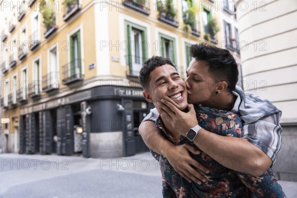 A joyful latin gay couple embraces in a cheerful moment while exploring the lively streets of Madrid. The colorful buildings create a vibrant backdrop, capturing love and happiness