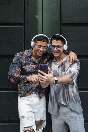 A happy couple in stylish outfits share a joyful moment with headphones and a smartphone. They smile while enjoying each other's company, embodying love and connection