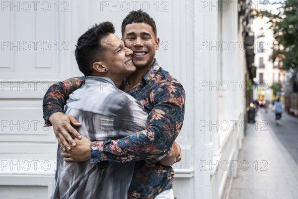 A joyful latin gay couple shares a warm embrace on a charming street in Madrid, reflecting love and happiness amidst the vibrant urban setting
