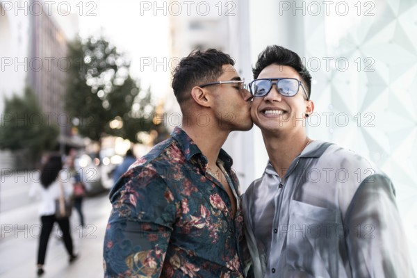 A happy latin gay couple enjoying an affectionate moment on a bustling street in Madrid, capturing love and joy during a sunny day in the city