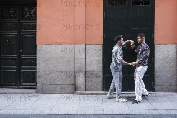 A joyful latin gay couple shares a moment of affection on a lively street in Madrid. Their happiness and connection illuminate the colorful urban backdrop