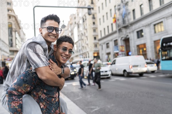 A happy latin gay couple smiles and embraces in the bustling streets of Madrid, showcasing love and joy amidst the vibrant city life, with iconic architecture in the background