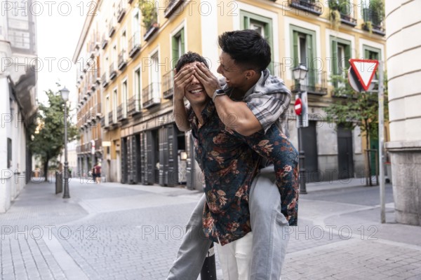 A happy latin gay couple enjoys a playful moment in the vibrant streets of Madrid. They are captured in a candid pose, exuding joy, love, and the spirit of the city