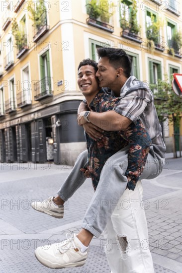 A joyful latin gay couple piggybacking on a picturesque street in Madrid. The colorful buildings and cobblestones add charm to their happiness