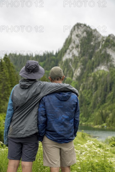Two people embrace while admiring the picturesque mountain landscape of Lac de Taney, Switzerland Lush greenery and serene water create a tranquil atmosphere perfect for nature lovers