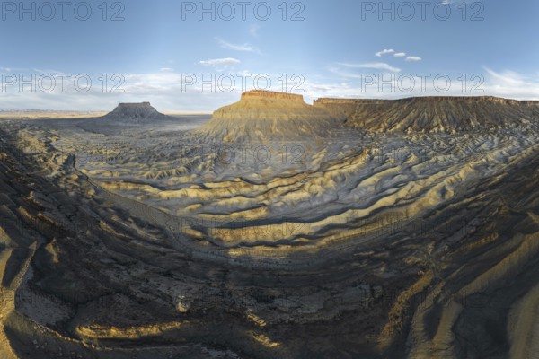 A breathtaking view of the rugged landscape of Caineville Mesa, Utah, USA, captured at sunset The light highlights the unique geological formations and vast desert scenery