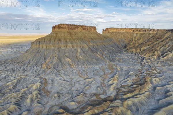 A breathtaking aerial view of Caineville Mesa in Utah, showcasing its impressive striated formations and unique geological textures under a vast blue sky