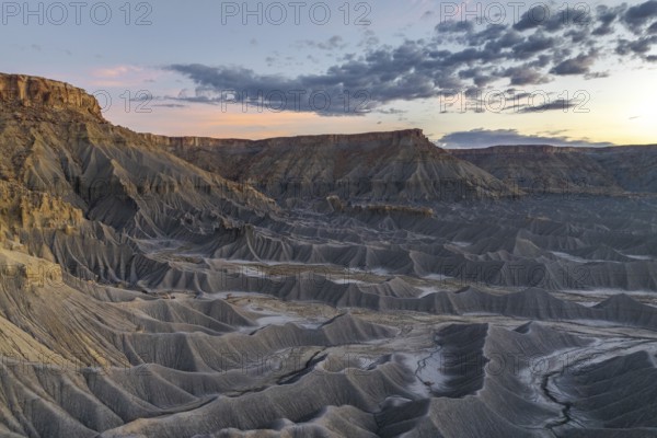 A stunning view of Caineville Mesa, Utah, showcasing dramatic geological formations under a vibrant sunset sky The scene captures the rugged beauty of this iconic landscape