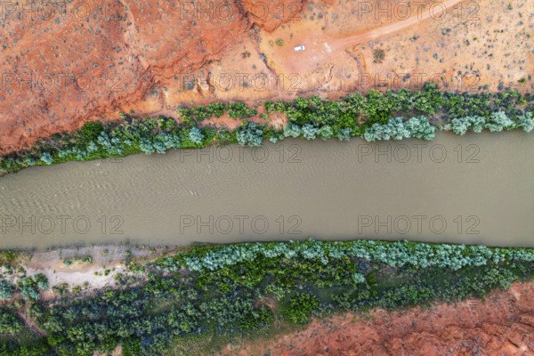 Stunning aerial shot captures the vibrant Rio San Juan slicing through Utah's red landscape, bordered by lush greenery