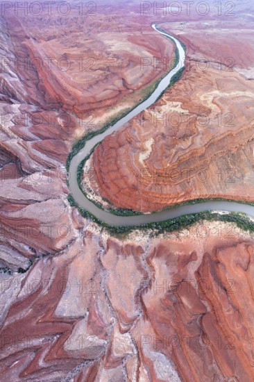 An aerial shot captures the serpentine path of Rio San Juan as it carves through the striking red rock formations of Utah, showcasing the natural beauty and geological diversity of the area