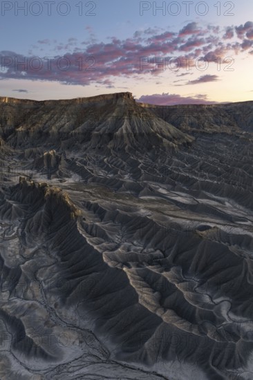 Dramatic view of Caineville Mesa in Utah at sunrise, showcasing unique geological formations and vibrant clouds Captivating landscape of rugged beauty and serene skies