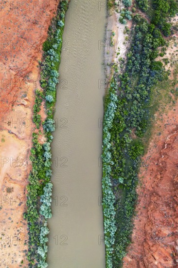 A striking aerial shot of the Rio San Juan winding through vibrant red rock landscapes, contrasted by lush greenery on its banks in Utah, USA