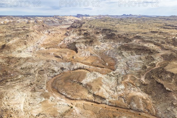 Aerial drone view captures the rugged and barren landscape of Hanksville, Utah, featuring winding dirt roads and sparse vegetation
