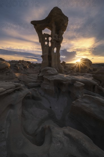 Dramatic rock formations in Bisti De-Na-Zin Wilderness, New Mexico, USA, are highlighted by the setting sun, casting a warm glow and emphasizing the rugged landscape