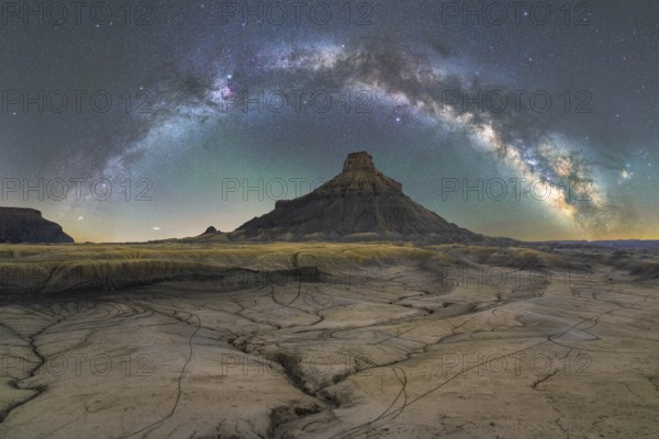 Stunning nighttime scene showcasing the Milky Way arcing over the dramatically textured landscape of Utah's desert, highlighting Earth's natural beauty under a star-filled sky