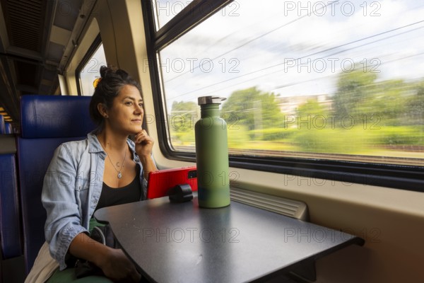 A thoughtful passenger gazes out a train window, absorbing the scenic landscape Sunlight filters through, creating a tranquil atmosphere perfect for travel reflection and relaxation