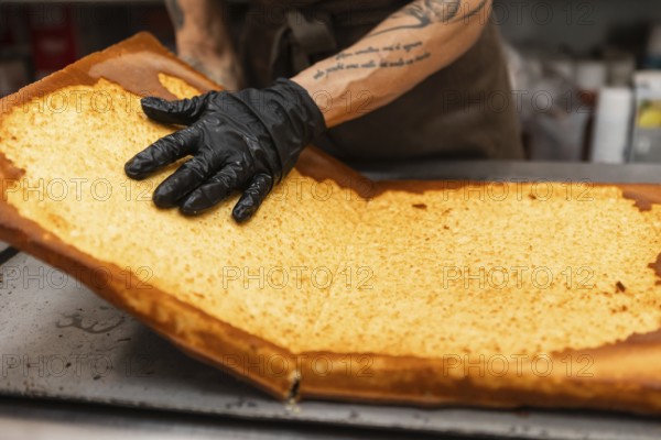 An artisan baker carefully handles a large sheet of golden-brown pastry in an Italian bakery The gloved hand demonstrates precision in crafting delicious baked goods