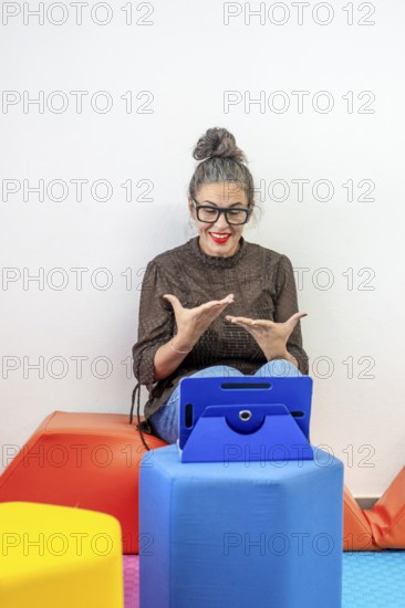 An engaging instructor teaches sign language through an online platform She's animated and expressive, seated on colorful cushions, as she interacts with a digital audience