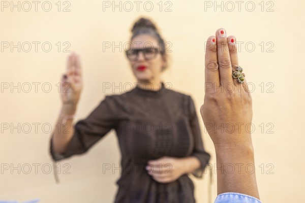 A focused image of a hand making a sign language gesture, with a background figure demonstrating Highlights communication, education, and the importance of sign language skills