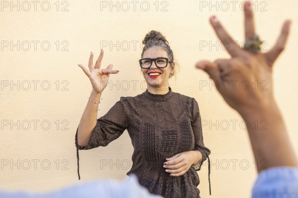 A cheerful instructor in glasses teaches sign language, engaging with a participant in an outdoor setting The close interaction highlights communication and learning