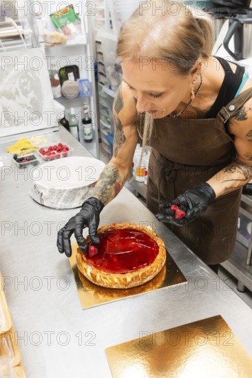 An artisan baker decorates a glossy fruit tart with fresh berries in an Italian bakery kitchen The culinary scene highlights the art and craft of traditional baking